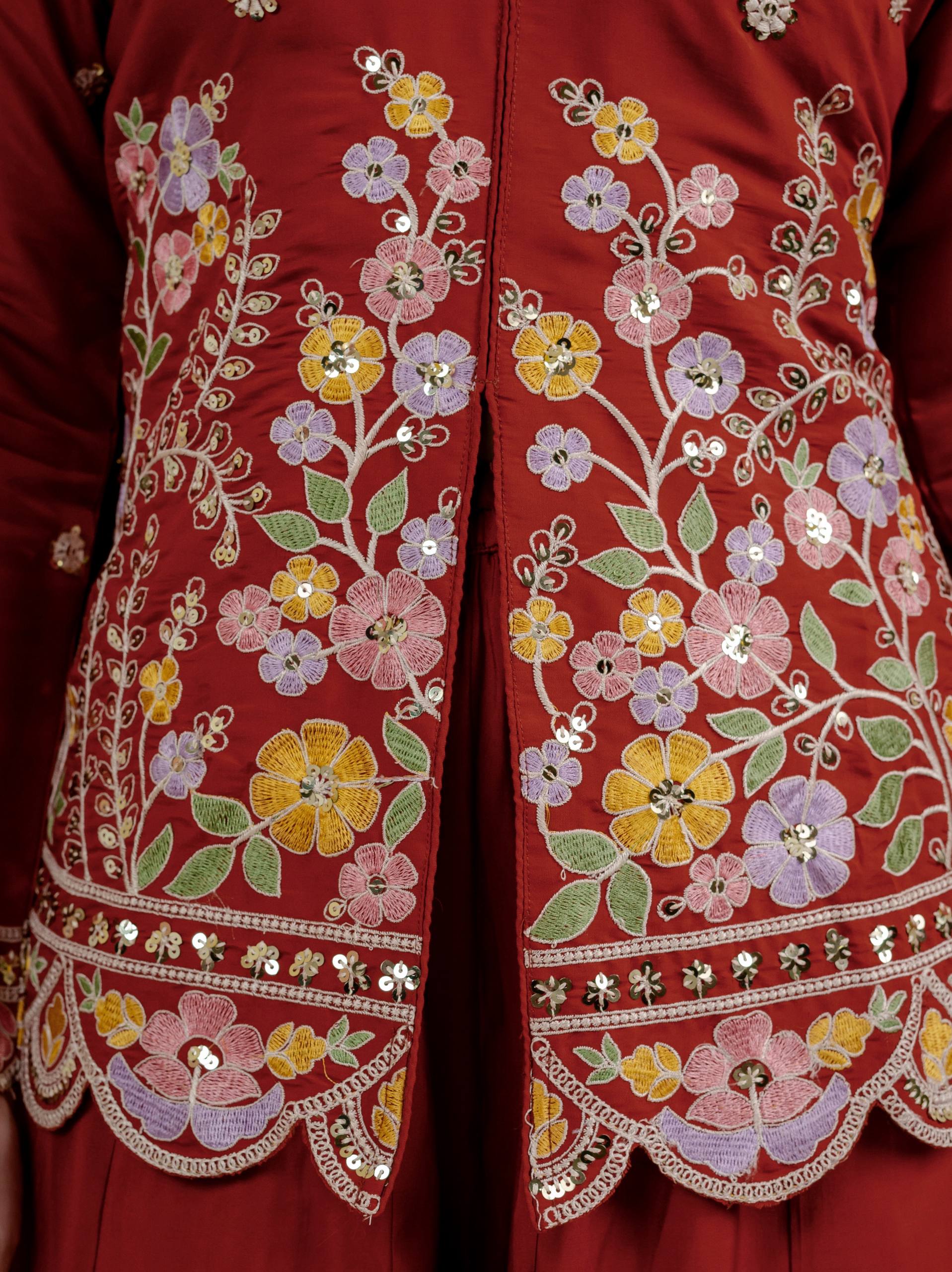 Resplendent Rust Orange Peplum Kurti and Flared Palazzo Suit Set Adorned with Intricate Multicolored Floral Embroidery, Sequin Accents, and Ornate Scalloped Borders